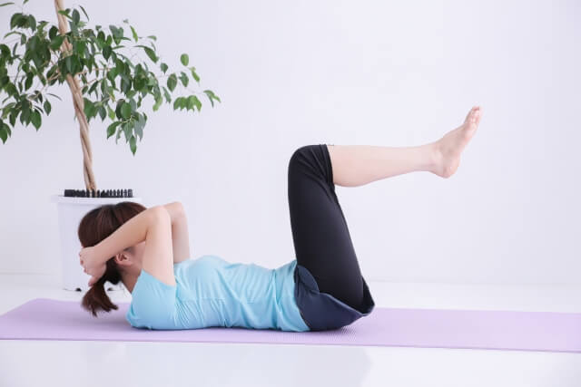 一人の女性が足を上げて腹筋トレーニングをしている写真