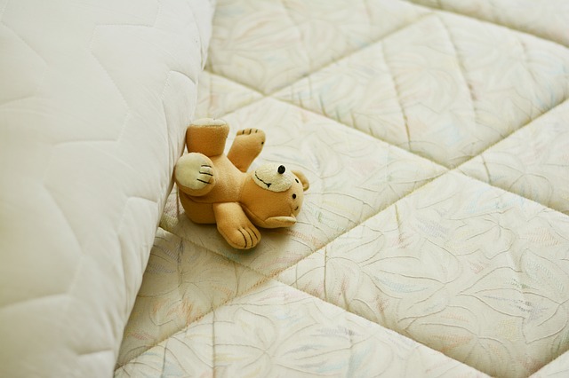 小さなクマのぬいぐるみがベッドに横になっている写真
